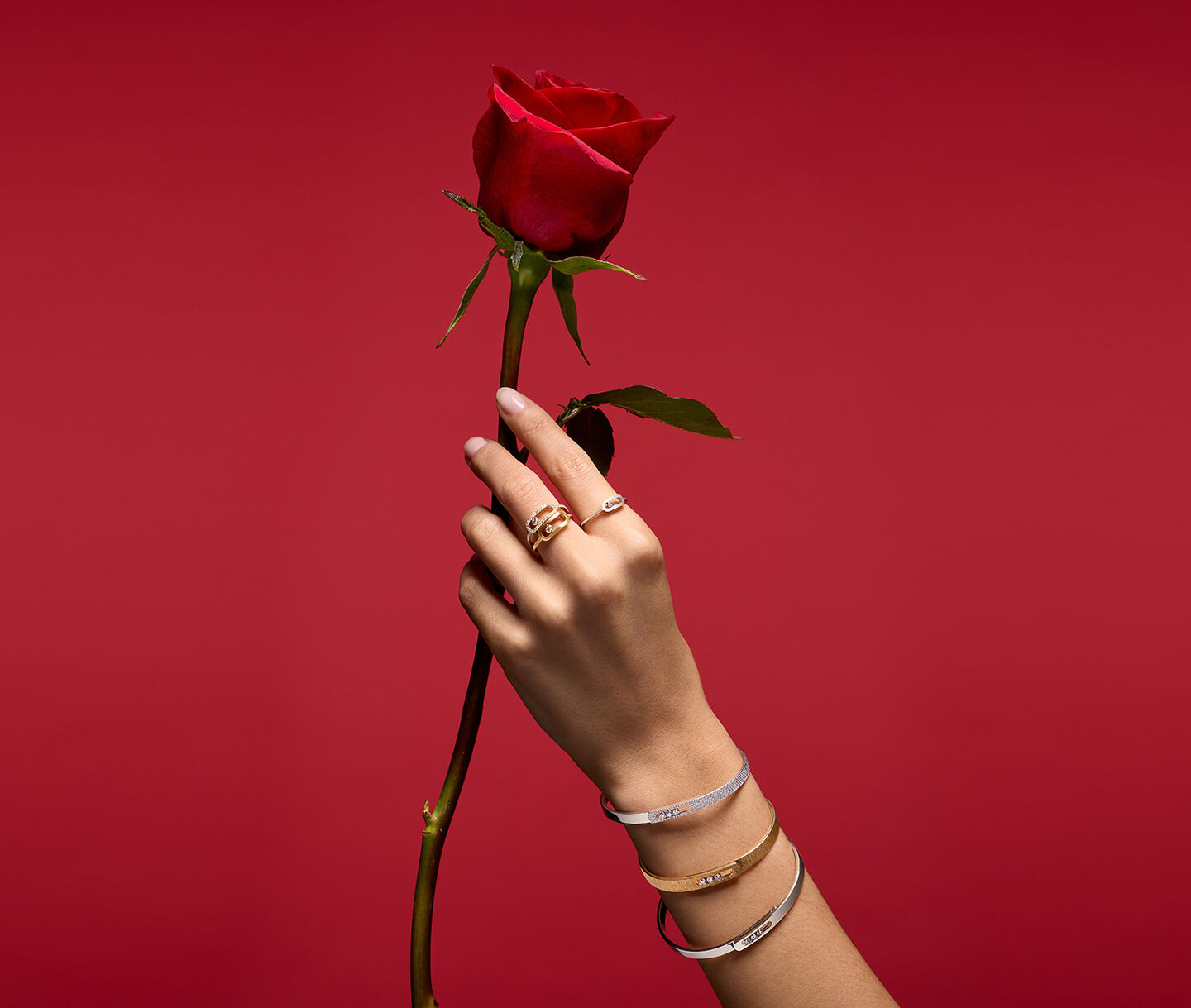 Une femme porte les bijoux Messika sur un fond rouge.